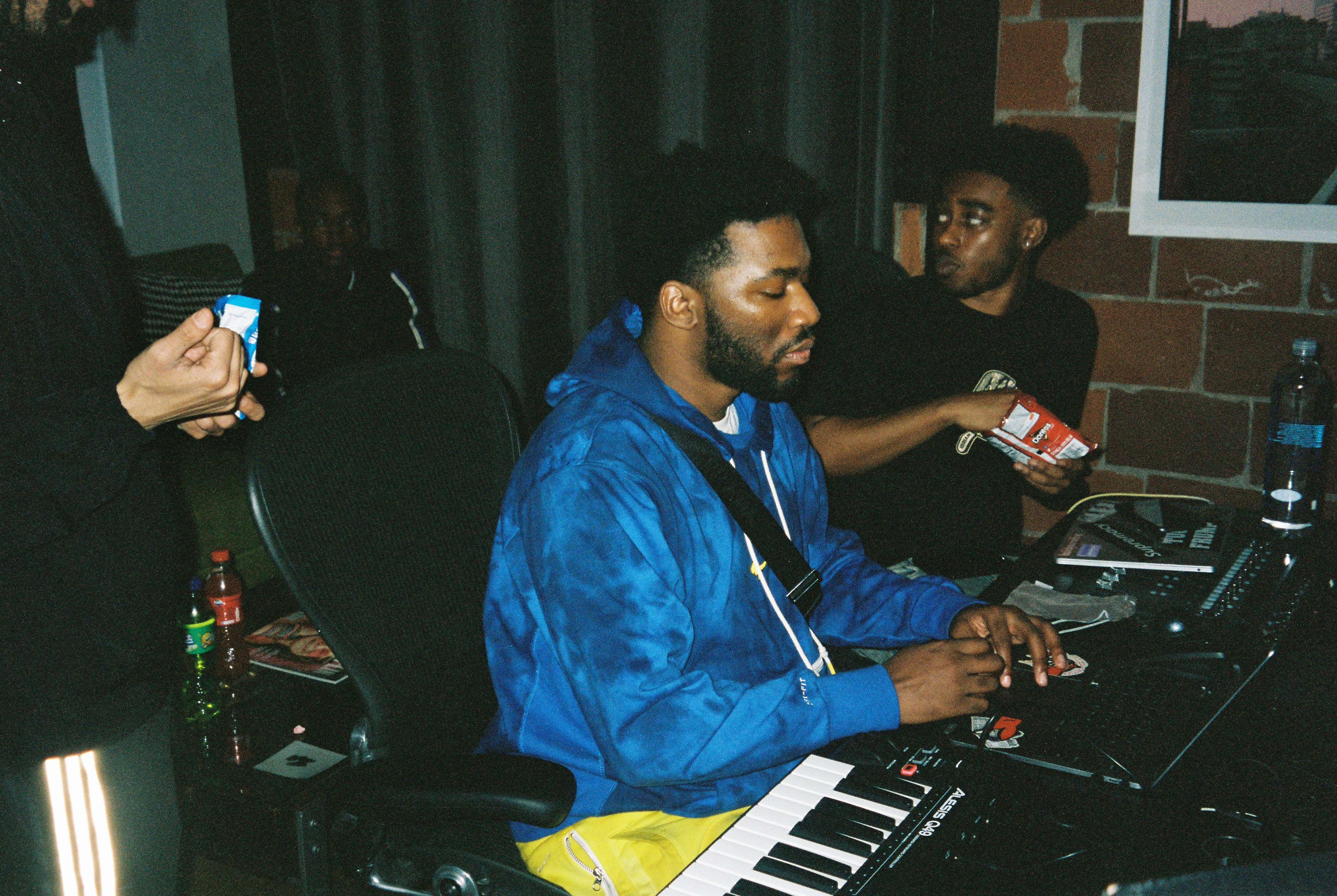 Artists in a studio session around a keyboard
